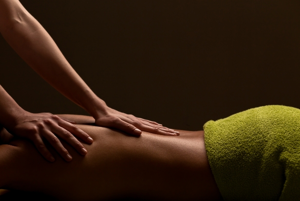 Image of a massage therapist giving a massage on a back with Wellness text overlay.